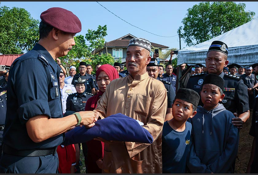 Mohd Khairi menyerahkan bendera Sang Saka Biru kepada Mazlan pada istiadat pengebumian hari ini. --fotoBERNAMA