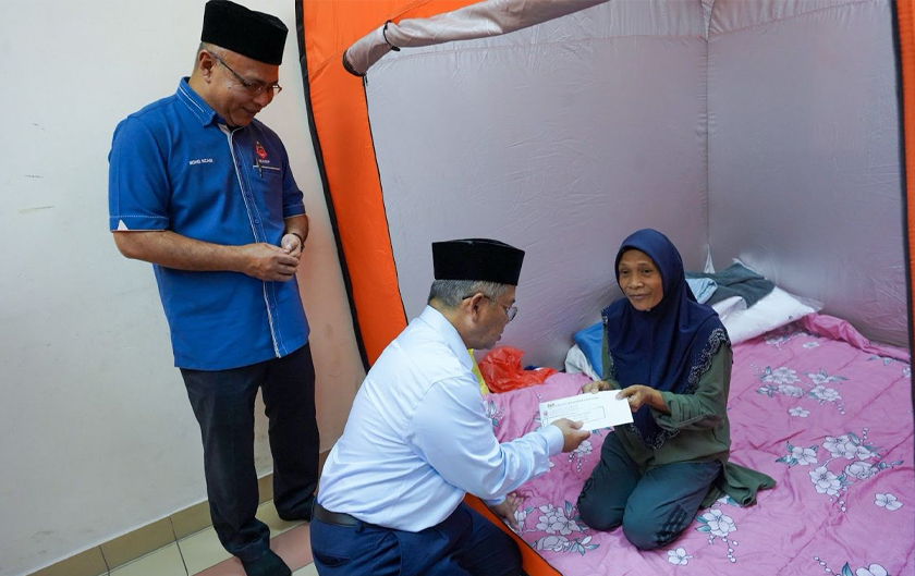 Datuk Dr. Mohd Na’im Mokhtar ketika memberikan sumbangan kepada salah seorang mangsa kebakaran kawasan Pantai Dalam. - Foto MAIWP