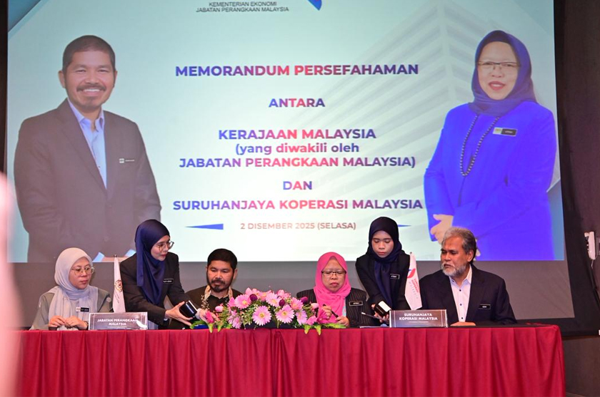 Uzir Mahidin dan Noor Afifah Abdul Razak menandatangani Memorandum Persefahaman bagi memperkukuh penyeragaman data koperasi antara DOSM dan SKM, disaksikan pegawai kedua-dua agensi. - Gambar DOSM
