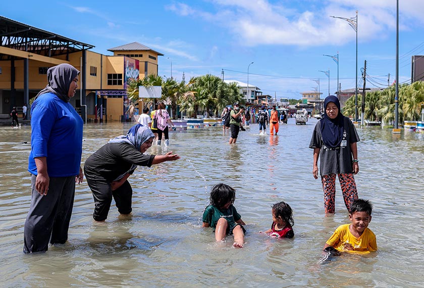Penduduk, Suziana Md Esa (dua dari kiri), tidak melepaskan peluang membawa anaknya bermain air susulan fenomena air pasang besar di Kukup hari ini. - Foto Bernama