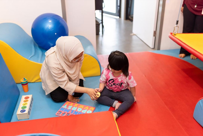 Naura (kanan) menjalani terapi yang dijalankan oleh Azimah Norsham, ahli terapi di Bilik Terapi Sensori Ronald McDonald, Tampin. - Foto McDonald's Malaysia