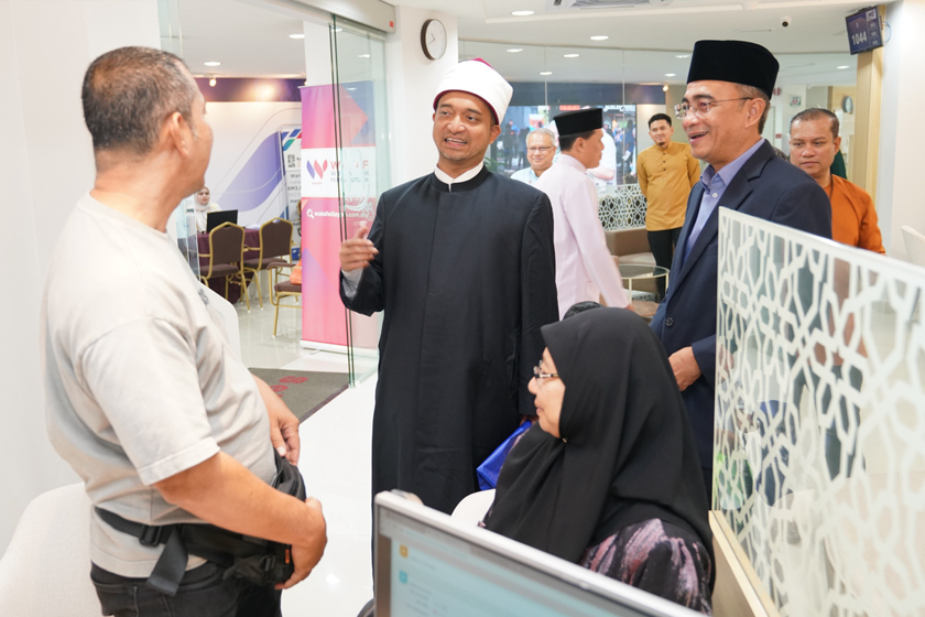 (Dari Kiri) Ahmad Fauwaz dan Mohammed Hassan ketika menyantuni orang ramai yang menunaikan zakat di di PPZ- MAIWP. - Foto PPZ-MAIWP