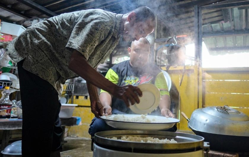 Arsad (kiri) menyiapkan hidangan Nasi Ambeng yang disajikan dalam talam untuk dihidangkan kepada tetamu di kediamannya di Gubok Pawon. --fotoBERNAMA