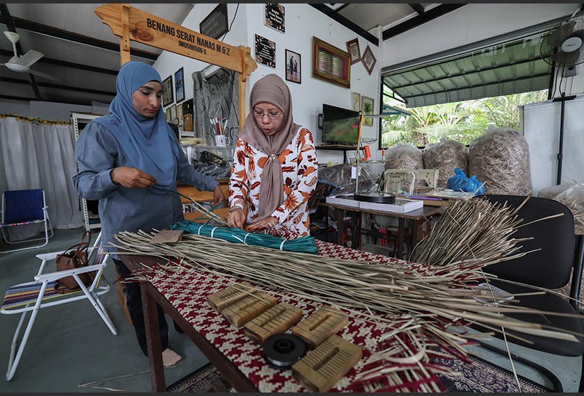 Usahawan benang serat nanas M & Z, Munah Abd Kadir, 52, (kanan) membuat anyaman daripada daun nanas ketika ditemui di Kampung Rimba Terjun baru-baru ini. Turut sama Pembantu Makmal LPNM, Noor Azizah Zainal. --fotoBERNAMA