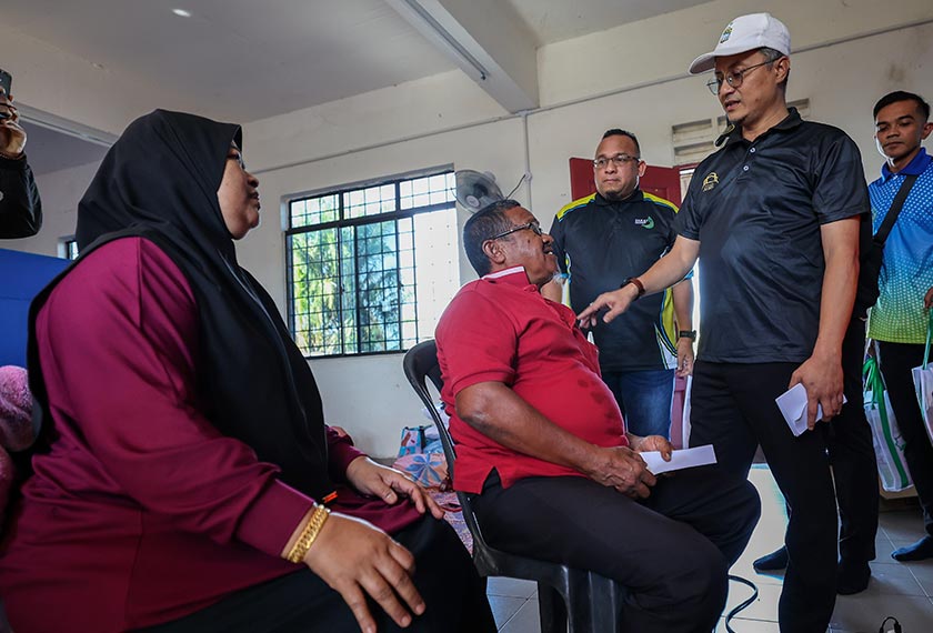 Timbalan Ketua Menteri I Pulau Pinang Datuk Dr Mohamad Abdul Hamid (dua, kanan) menyantuni mangsa banjir yang ditempatkan di PPS Labuh Banting, Seberang Perai. - Bernama