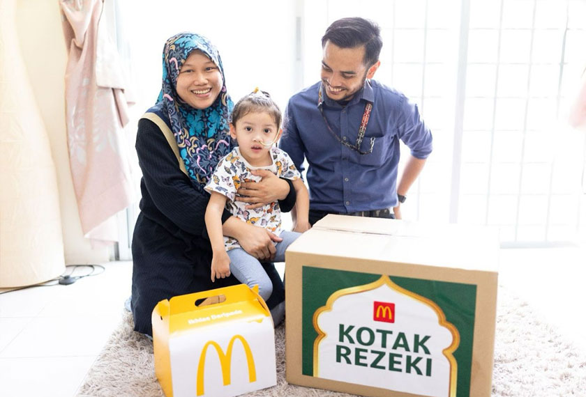 Muhammad Nuh Mubin Mahdan (kanan) dan anaknya, Nuha Humaira Muhammad Nuh Mubin (tengah) yang menghidap penyakit Celebral Palsy, kelihatan gembira selepas menerima Kotak Rezeki dan makanan McDonald's kegemaran ramai. - Foto McDonald's Malaysia